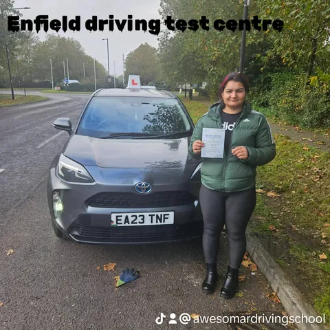 Pupil holding a driving test pass certificate outside Enfield driving test centre