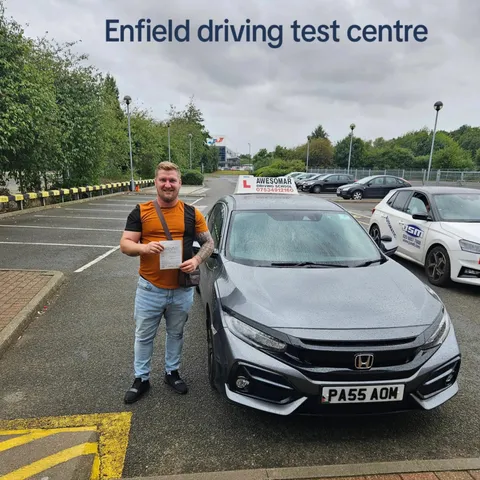 Pupil holding a driving test pass certificate beside the school car